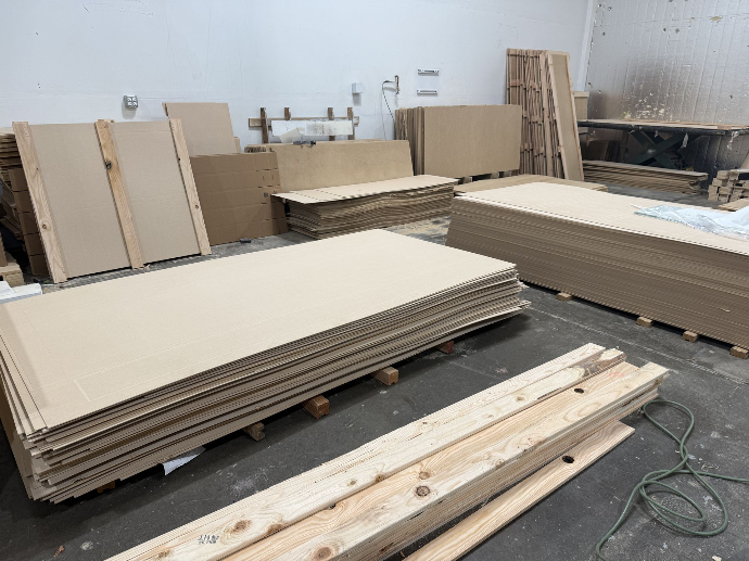 Rigid crate wall panels and custom foam components staged for building one-way shipping crates.